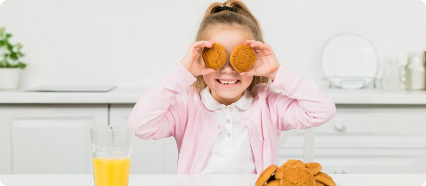 Niña sosteniendo dos galletas — mostrando cómo contamos cosas como “galletas” en inglés (sustantivos contables)