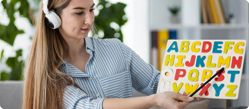 Professional teacher using headphones and an alphabet puzzle to evaluate a child’s English level