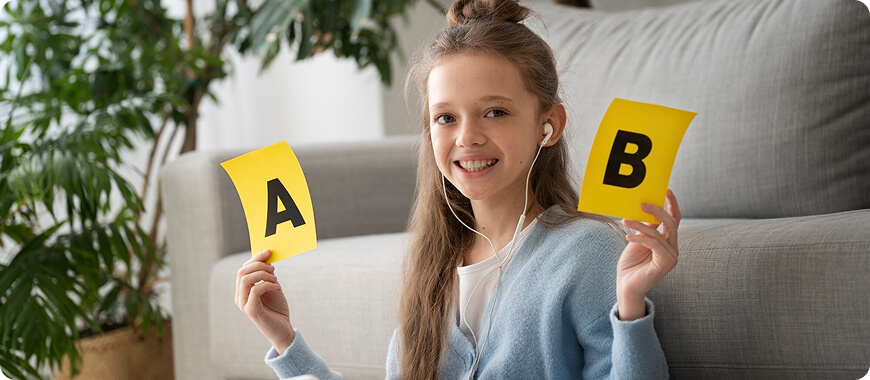 Child holding alphabet cards while learning English with headphones